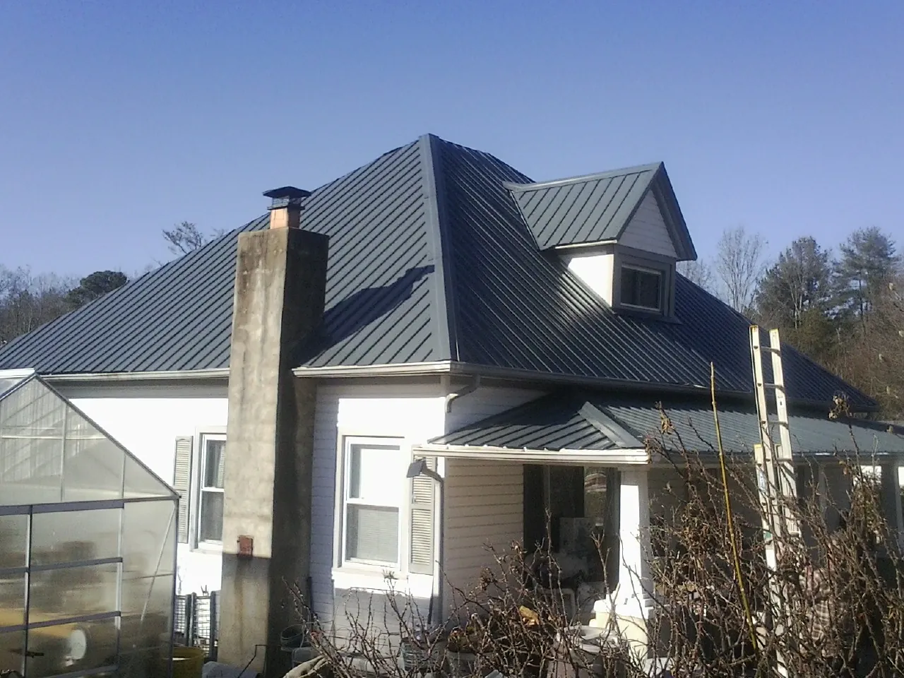 Dark blue standing seam metal roof on a white farmhouse with dormer — Slate & Tile Roof Repair by Roofing Brothers in Fort Hall