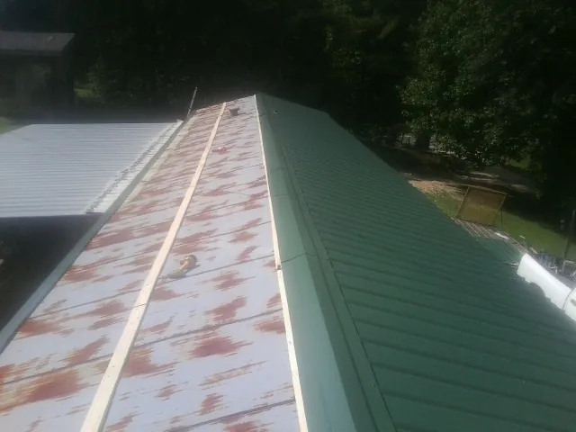 Old rusted panels beside newly installed green metal roofing — Wind Damage Roof Repair by Roofing Brothers in Fort Hall