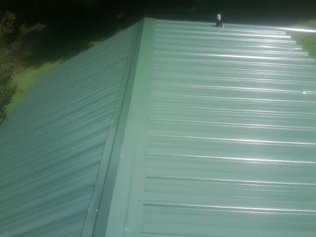 New green metal panels meeting at the ridge of a roof — Flat Roof Repair work by our crew in Fort Hall