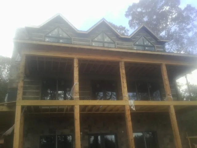 Dormers and porch framing on a large log home under construction — Roof Coating work by our crew in Fort Hall