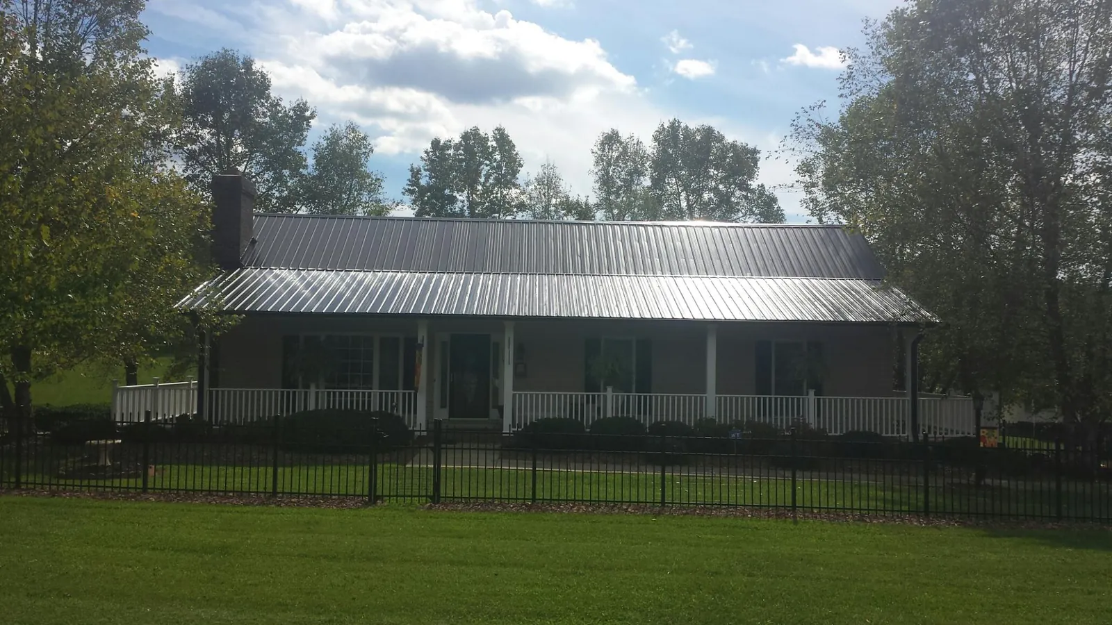 Gray metal roof on a brick ranch with a full width front porch — Gutter Guard Installation work by our crew in Fort Hall