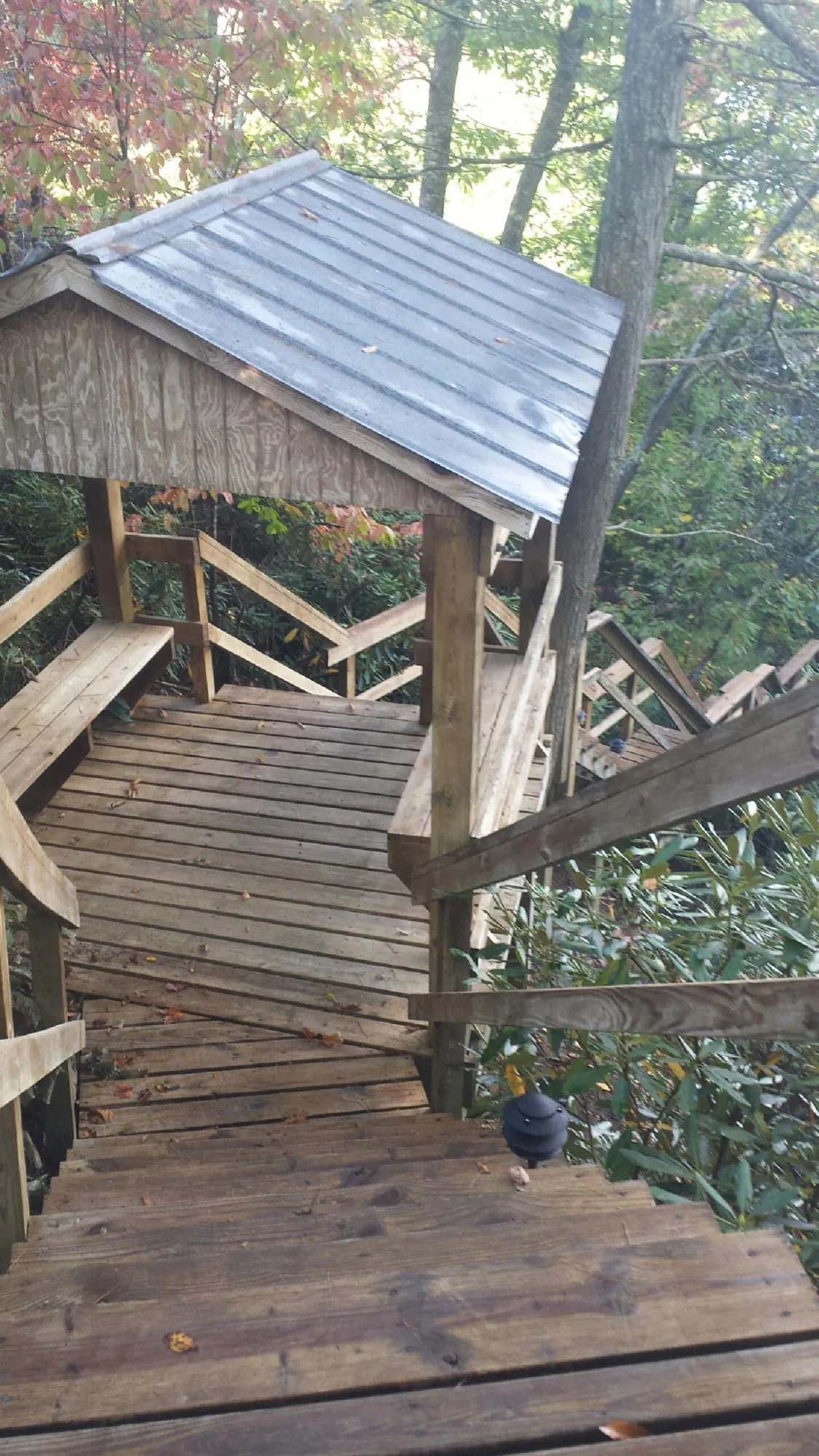 Metal roofed shelter over wooden steps on a wooded walkway — Skylight Repair & Installation work by our crew in Fort Hall