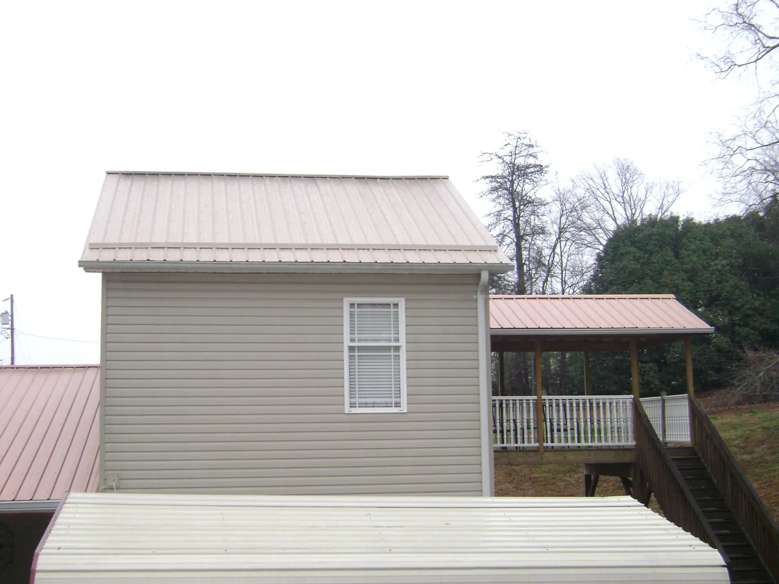 Tan metal roofs on a two story addition and attached porch, from a Roof Replacement job in Fort Hall