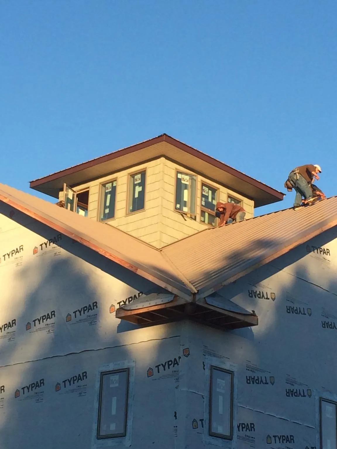 Roofers working around a rooftop cupola on a new metal roof at sunset — Roof Waterproofing in Fort Hall by Roofing Brothers
